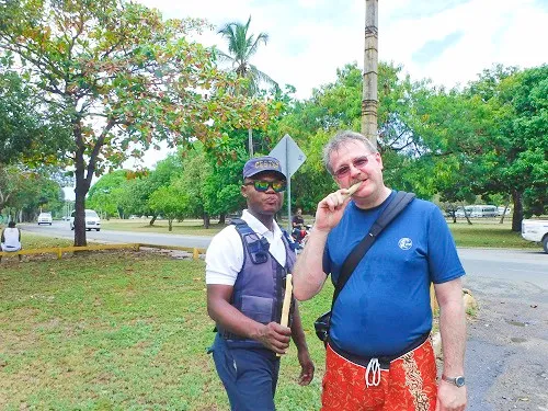 Rudy eating sugarc ane and a policeman during a Walking tour of La Romana