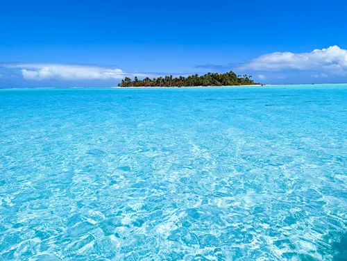 Motu with palm trees surrounded by turquoise water in Aitutaki Lagoon in the Cook Islands