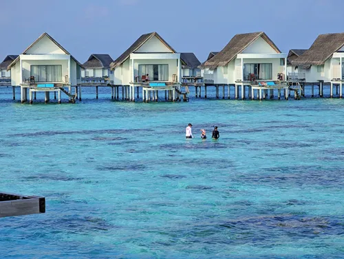 Overwater Bungalows and people snorkeling at Centara Grand in the Maldives