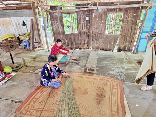 two women demonstrating how to weave a carpet. This demonstration occurred during a guided Mekong Delta tour in Ben Tre in Vietnam