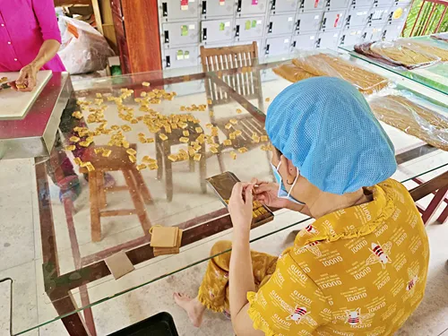 woman wrapping freshly made cocnut candy in wrappers during a guided Mekong Delta tour in Ben Tre in Vietnam