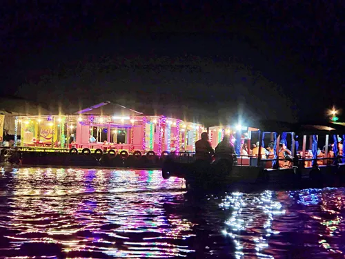 photo taken from a boat in the early morning before sunrise of illuminated boats along the river in Can Tho in Vietnam