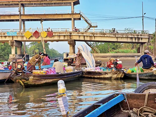 Vietnamese women on small boats examining and trading goods at Phong Điền Floating Market near Can Tho in Vietnam