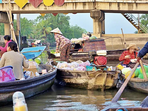 Vietnamese women on small boats examining and trading goods at Phong Điền Floating Market near Can Tho in Vietnam