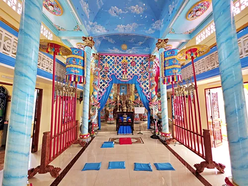 photo of a hallway with cloudy-sky ceiling and a colorful altar in the background at Cao Dai Temple in Ho Chi Minh City, Vietnam