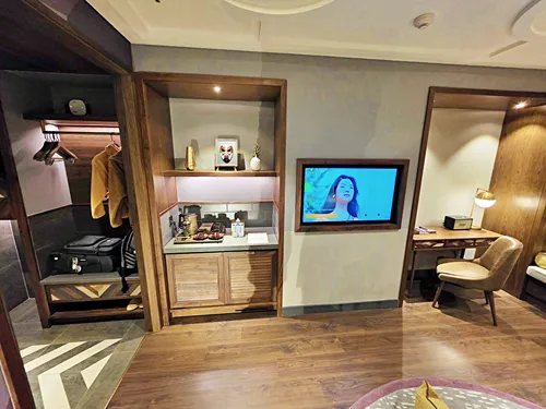 photo of a bedroom showing the table, TV, mini bar and storage at the Fusion Original Saigon Centre in Ho Chi Minh City in Vietnam