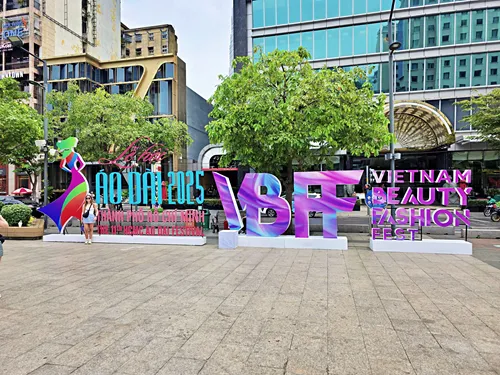 photo of Nguyen Hue Promenade in Ho Chi Minh City, Vietnam, showing people in beautiful traditional dresses and traditional decorative stands that are erected on the promenade