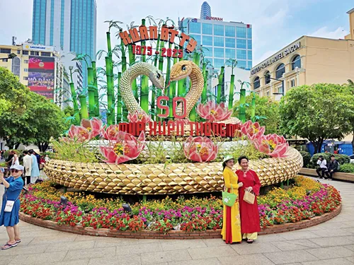 photo of people in beautiful traditional dresses posing in front of a traditional decorative stand on Nguyen Hue Promenade in Ho Chi Minh City, Vietnam