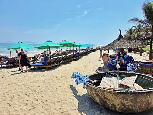 photo of people laying on beach chairs and under beach umbrellas at An Bang Beach near Hoi An in Vietnam