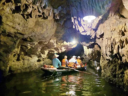 photo inside a cave showing another sampan with tourists in the water in Ninh Binh in Vietnam